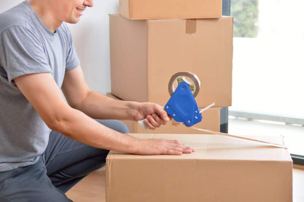 A man is sealing a box with packing tape