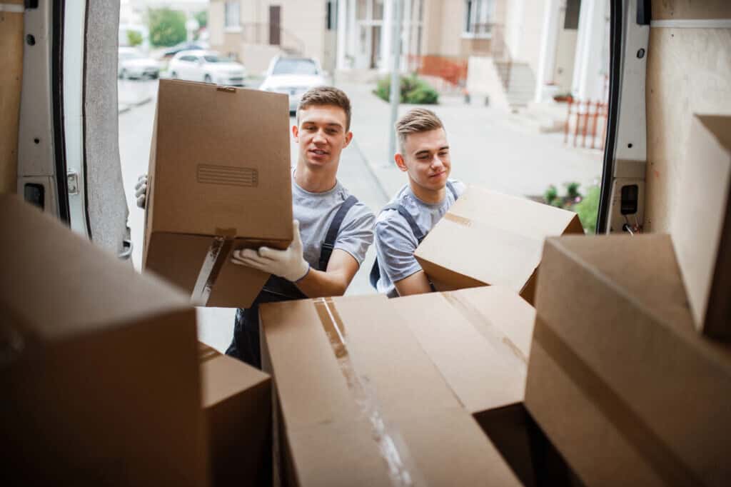 Two workers at the back of the van full of cardboard boxes