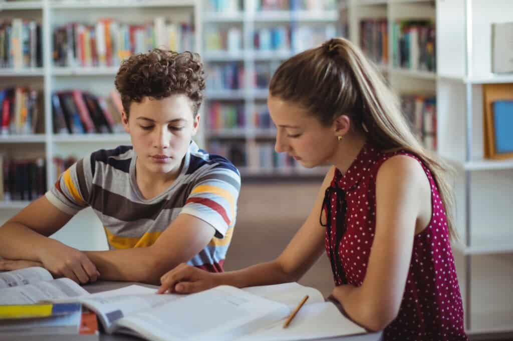 Classmates working on their homework at the library in the concept ot 'top schools in Bromley'.