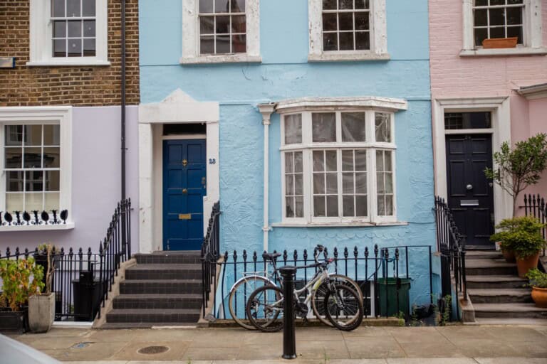 Pastel-coloured houses with handrails and a bike parked outside in the concept of 'best affordable housing options in Bromley'.